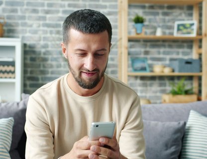 A homeowner searching for a roofing contractor on a smartphone at home