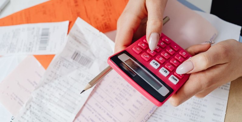 Working out contractor website cost on a calculator beside a stack of receipts
