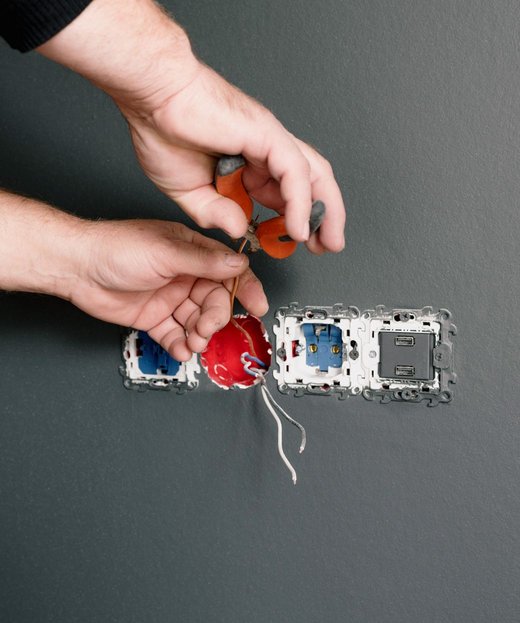 An electrician wiring a bank of outlets into a wall