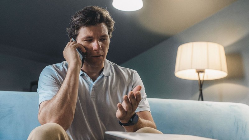 A homeowner on the phone at home, trying to reach an HVAC contractor
