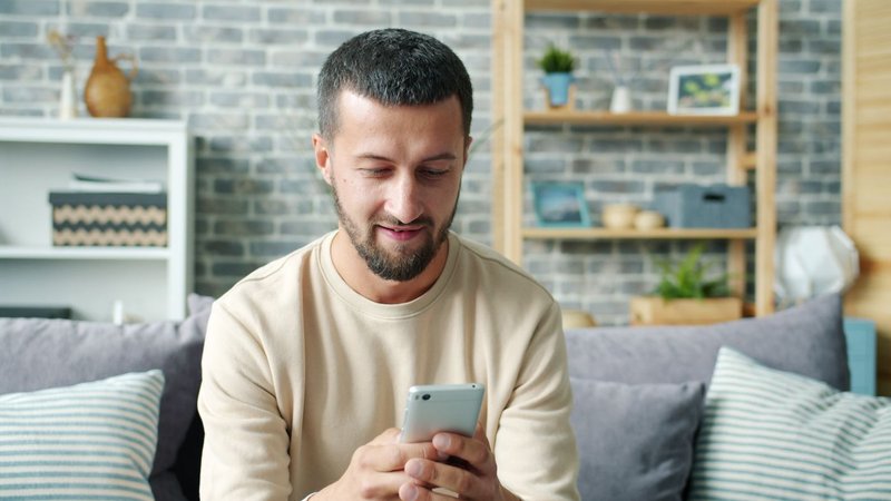 A homeowner searching for a roofing contractor on a smartphone at home