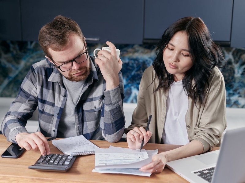 A couple reviewing an HVAC invoice and using a calculator at their kitchen table