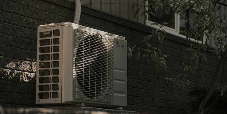An air conditioning condenser unit mounted on an exterior wall