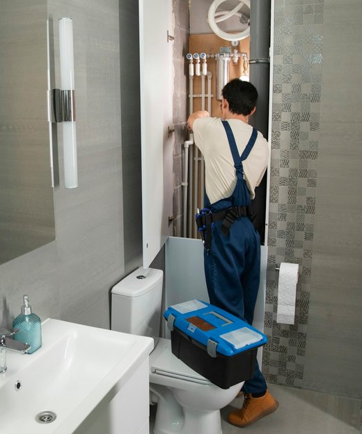 A plumber fitting pipework under a bathroom sink