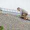 A roofing contractor laying shingles on a pitched roof