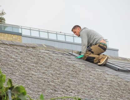 A roofing contractor laying shingles on a pitched roof