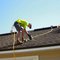 A roofer working on a pitched roof with a power drill