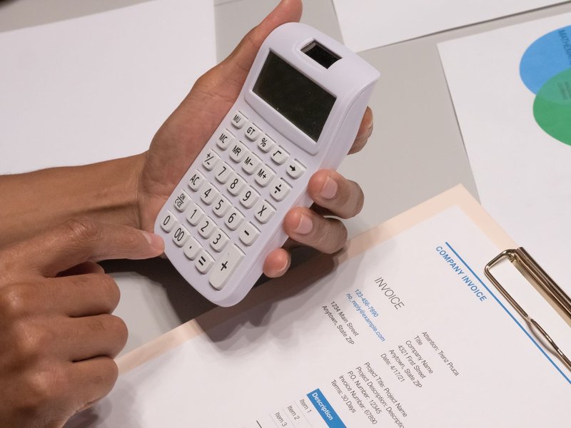A homeowner comparing roofing quotes with a calculator and an invoice